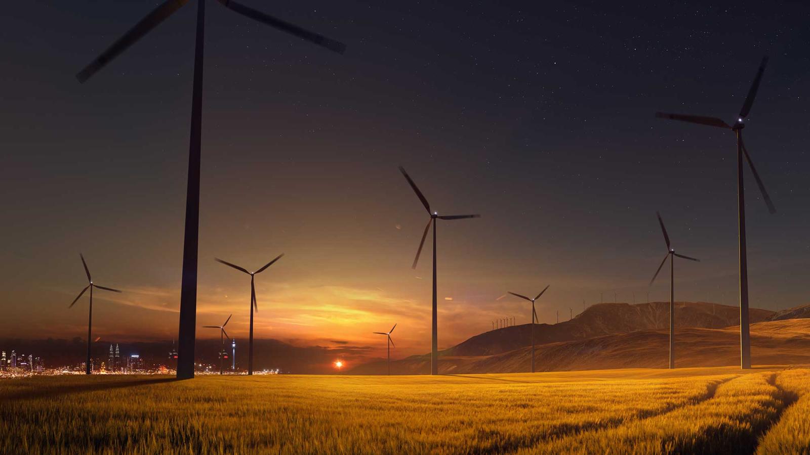 wind turbines in a field at sunset with a city in the background