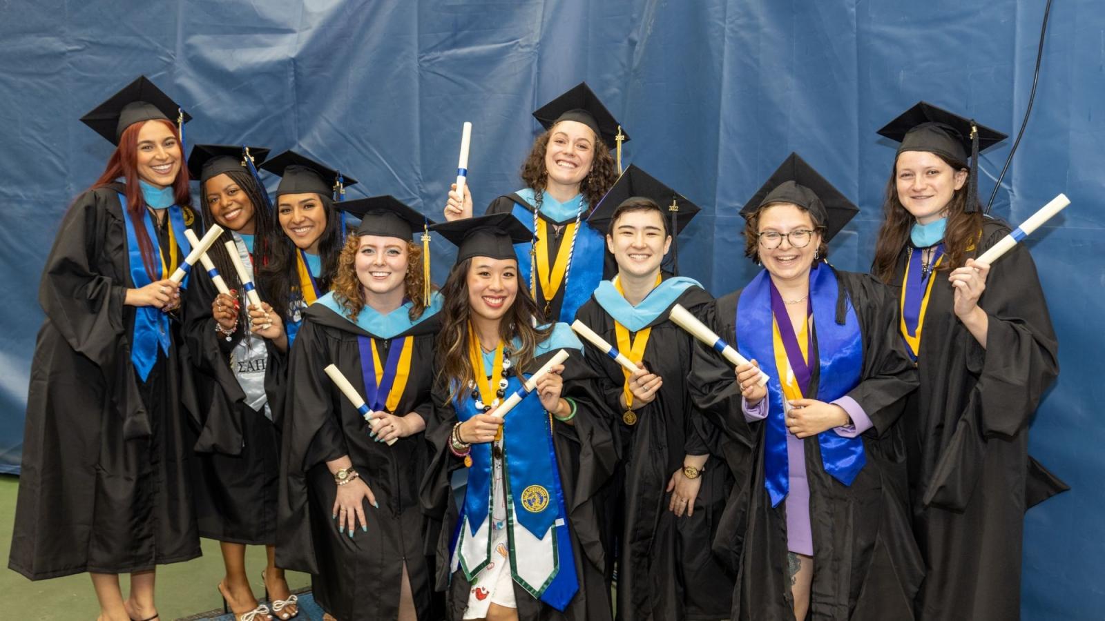 graduates with cap and gown smiling