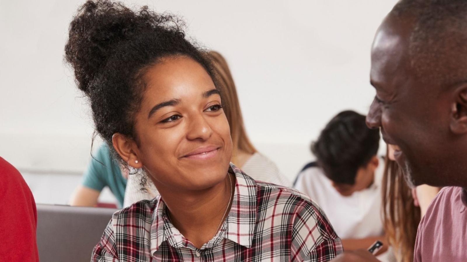 Two students in class talking and smiling.