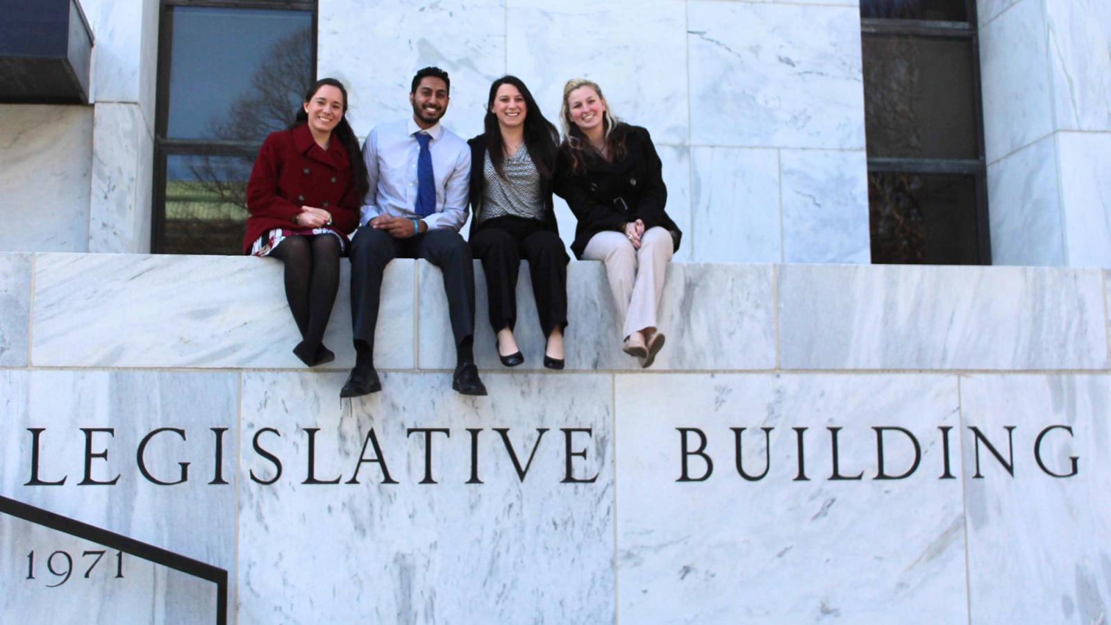 Four Pace students sitting on the balcony of the NYS Legislative Building