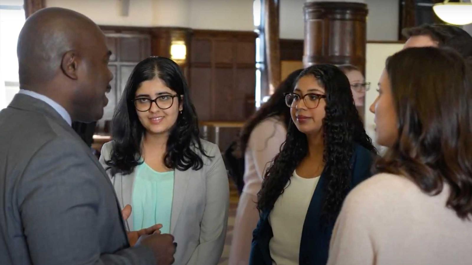 Four individuals conversing in a professional setting on the Elisabeth Haub School of Law campus