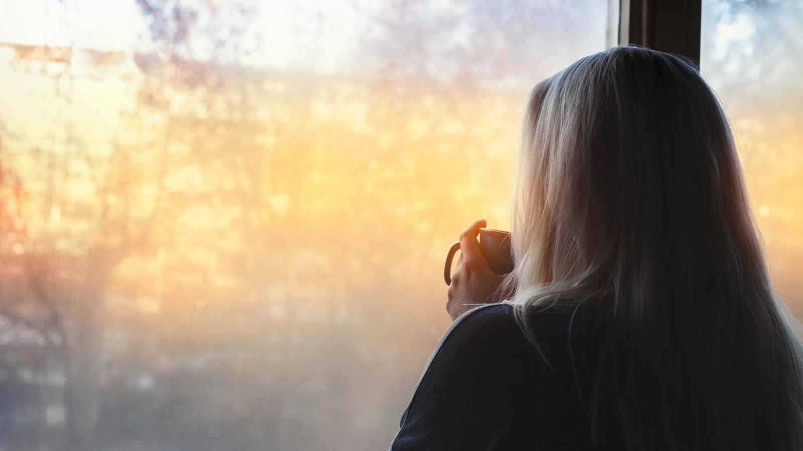 Woman looking out of the window on a bright new day