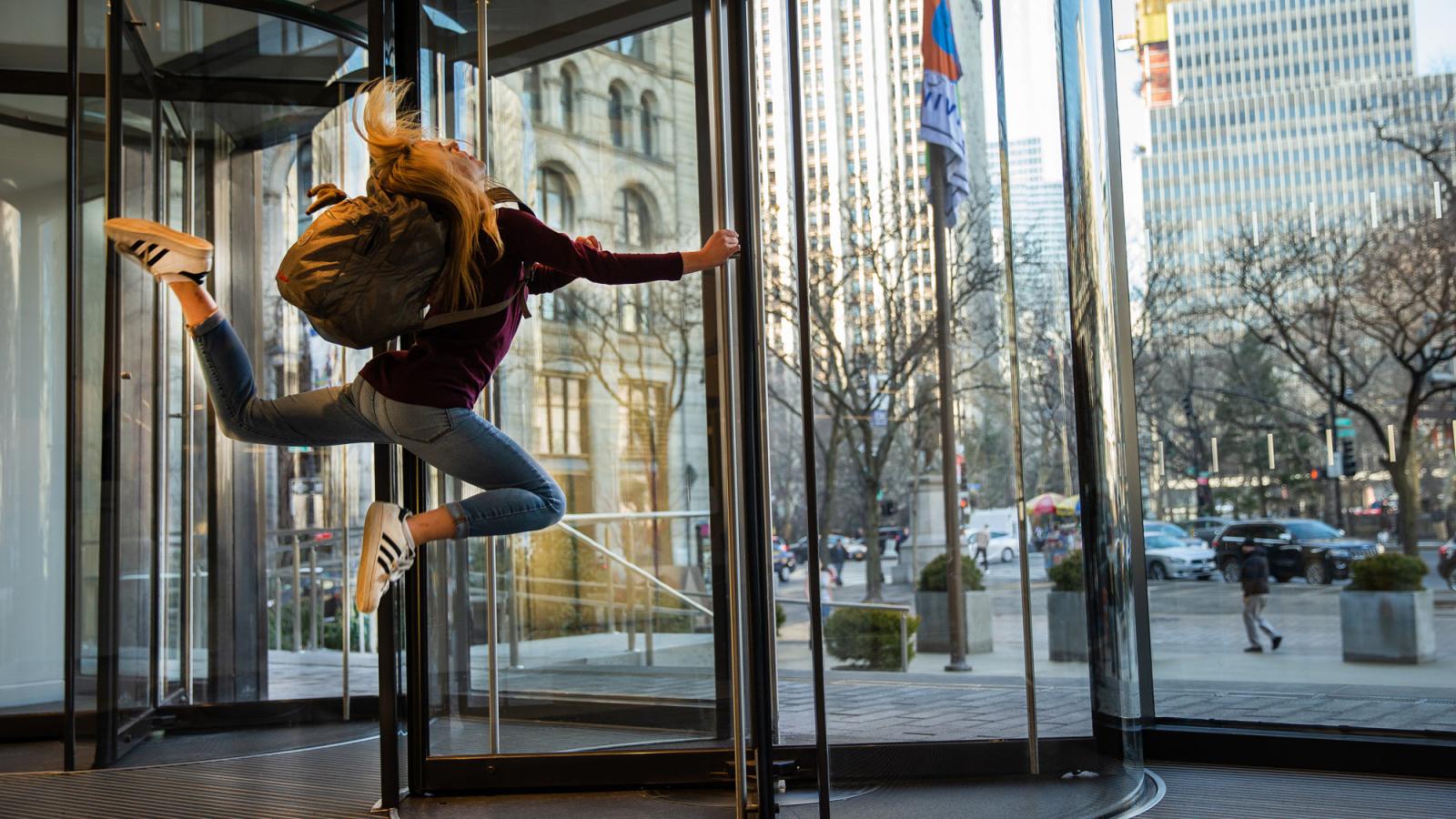 Pace student jumping in mid-air as she exits the front of One Pace Plaza