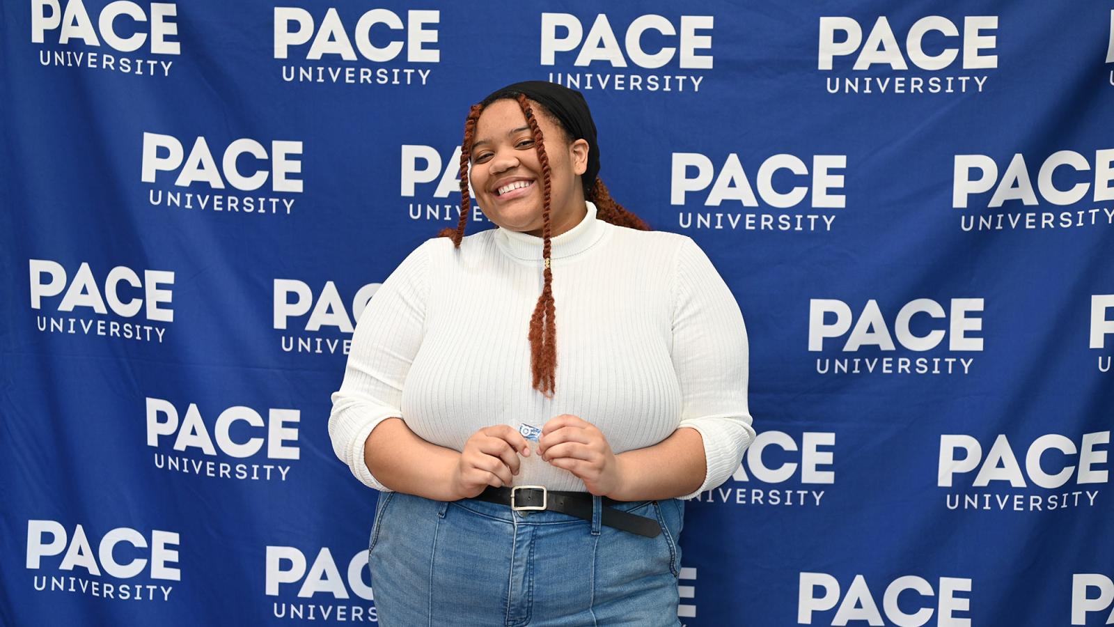 Student Danielle Shoulders stands in front of a blue Pace backdrop