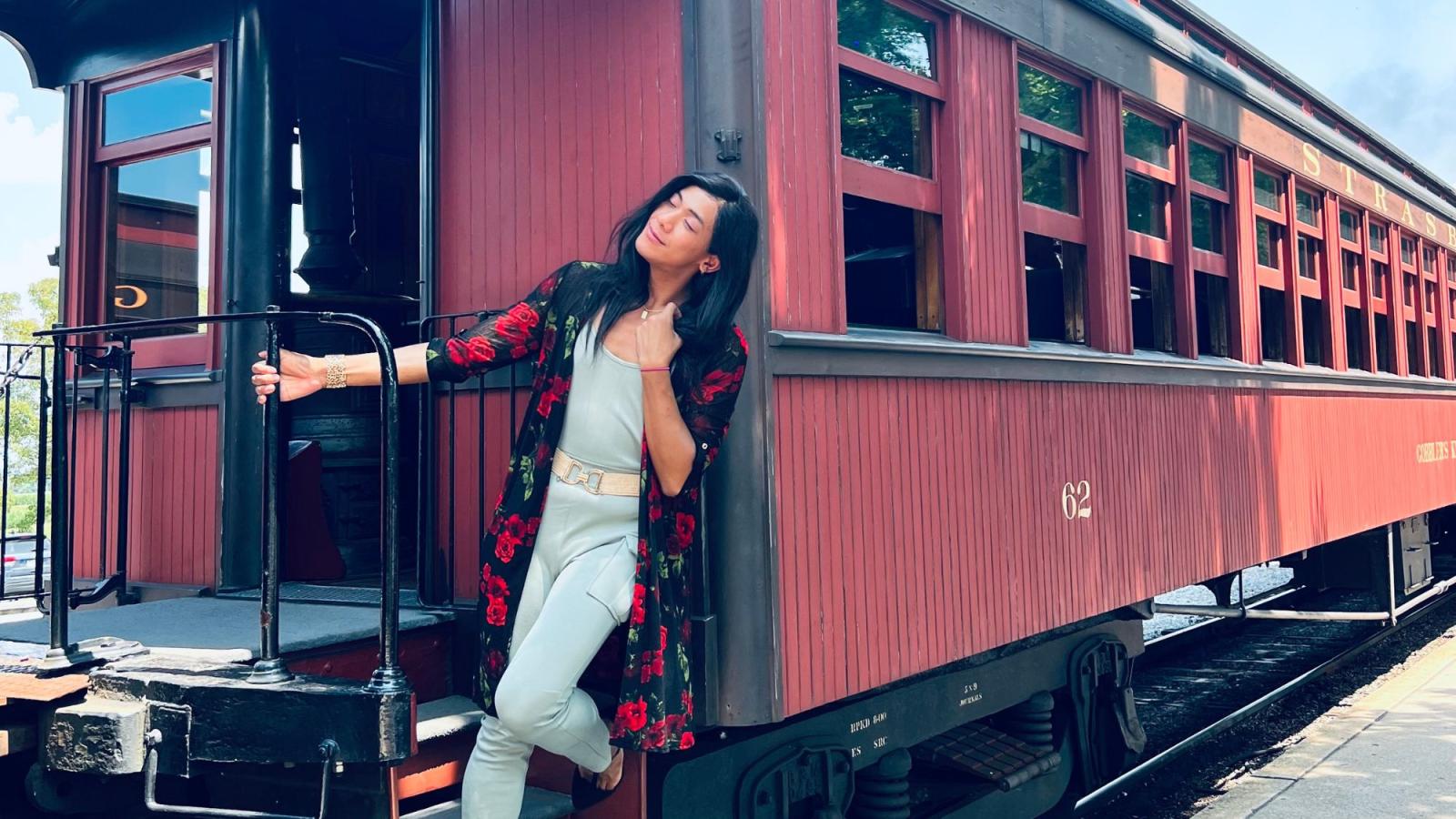 Seidenberg alum Mochii De Castro poses at the front of a train car