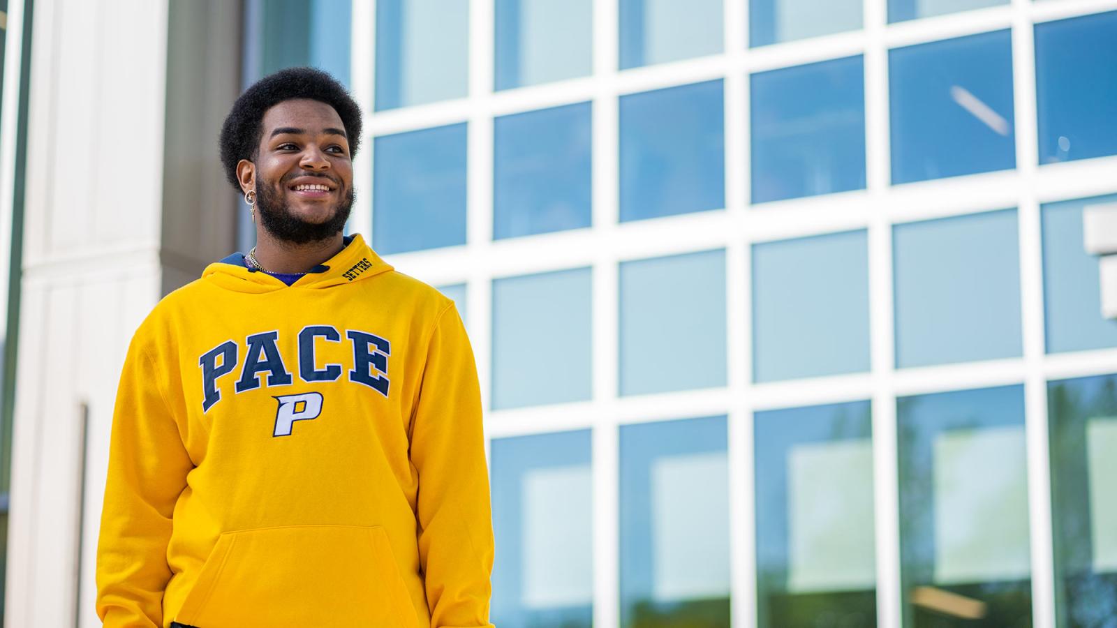 Pace student D'Andre Butler stands in front of a windowed building on the Pleasantville Campus
