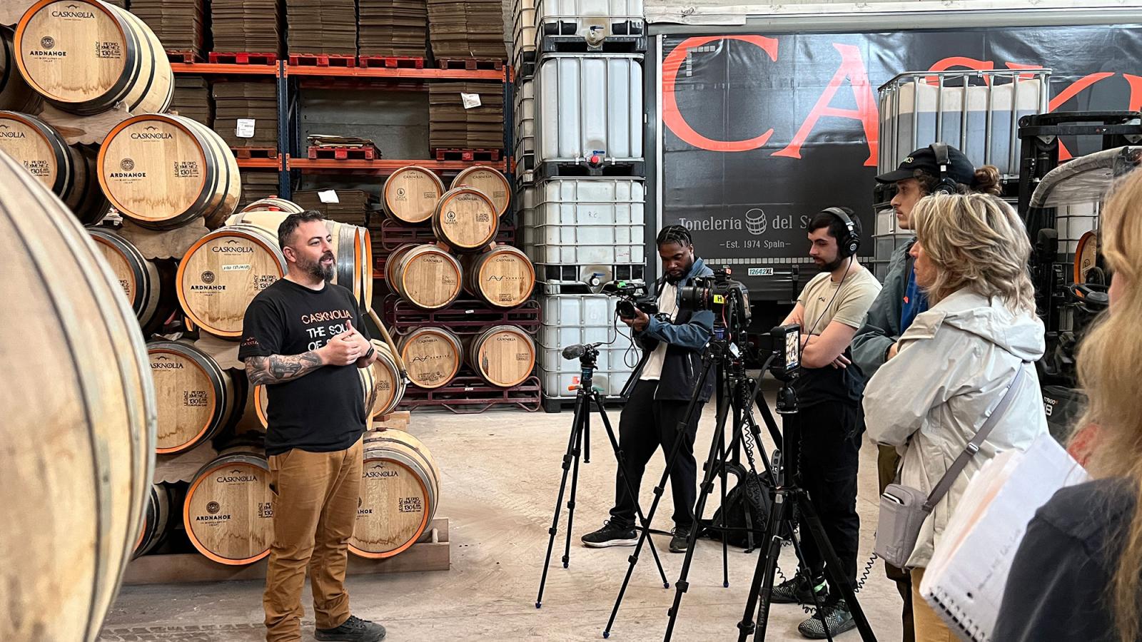 Pace University's Media, Communications, and Visual Arts PaceDocs documentary students in Spain filming a person speaking about casks with barrels in background