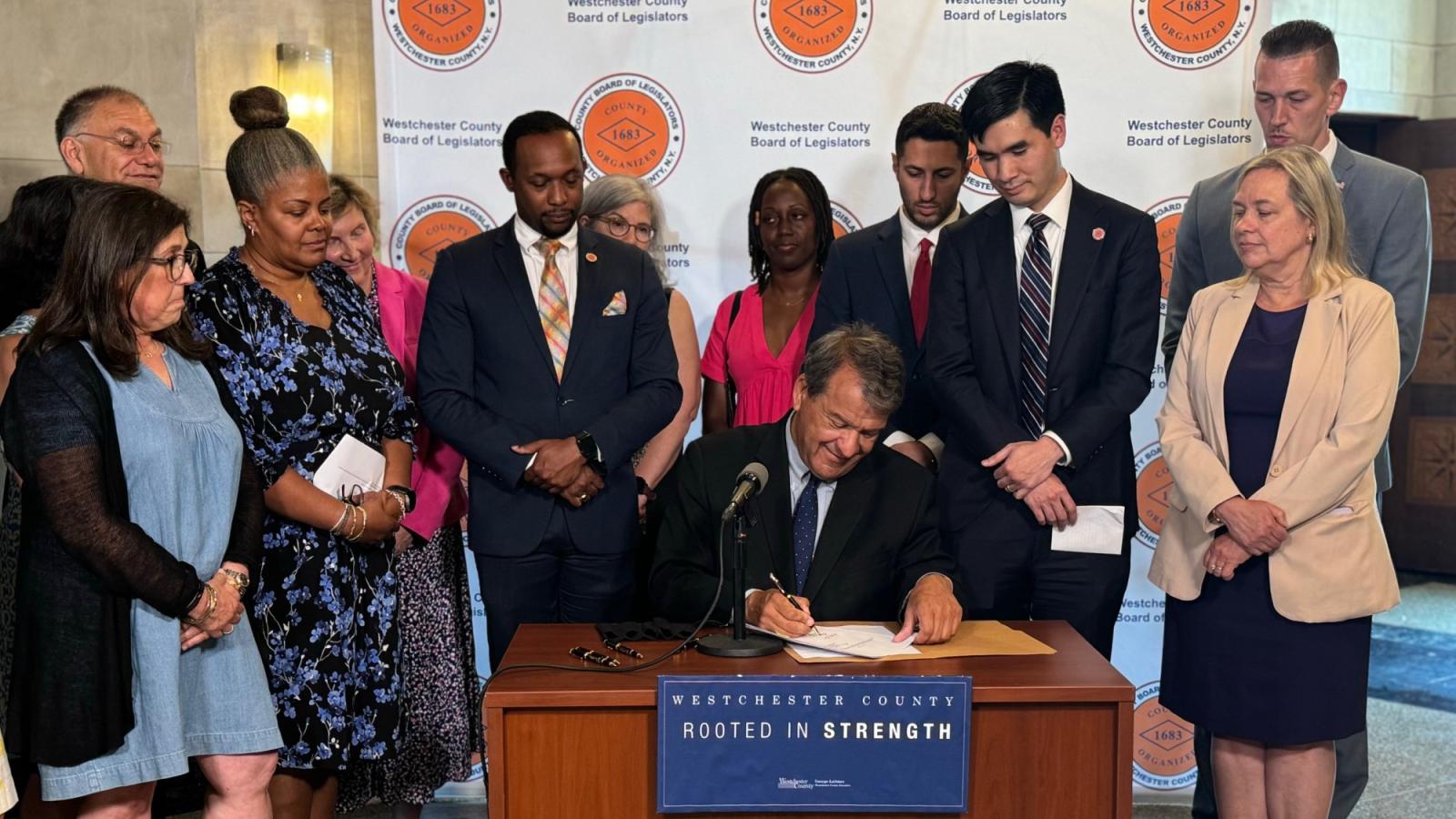 George Latimer signing a domestic violence law with spectators watching including Elisabeth Haub School of Law PWJC's Cindy Kanusher