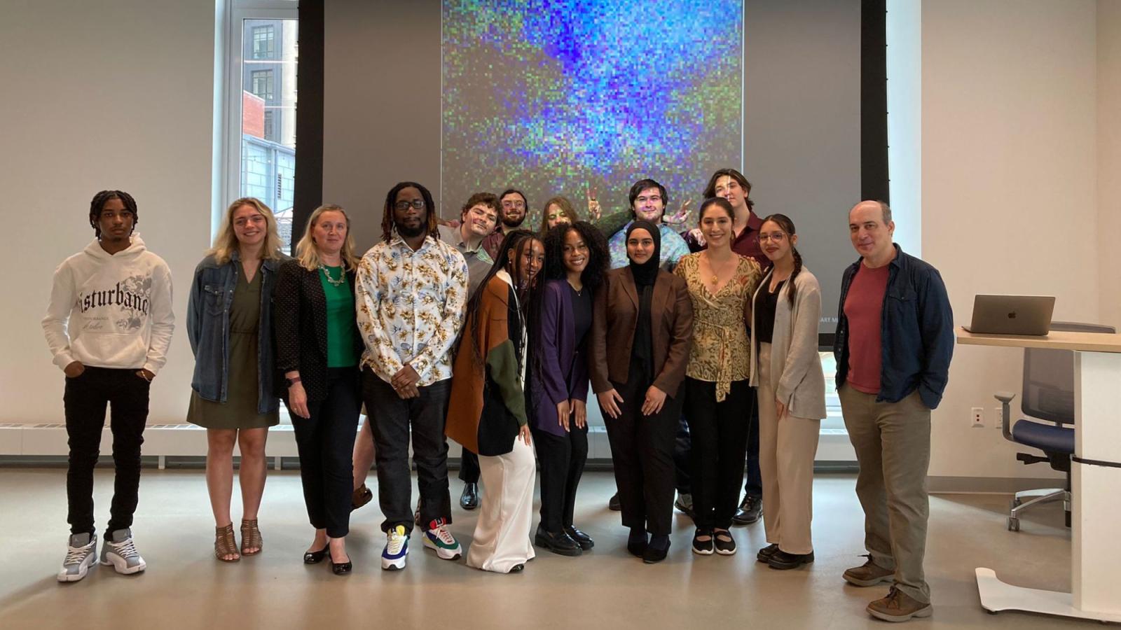 Pace Seidenberg students who interned at the 2024 AI Internship Experience Program posing for a group photo with program leads Dr. Christelle Scharff and Dr. Carmine Guida in front of an AI-generated image at the Seidenberg Design Factory.