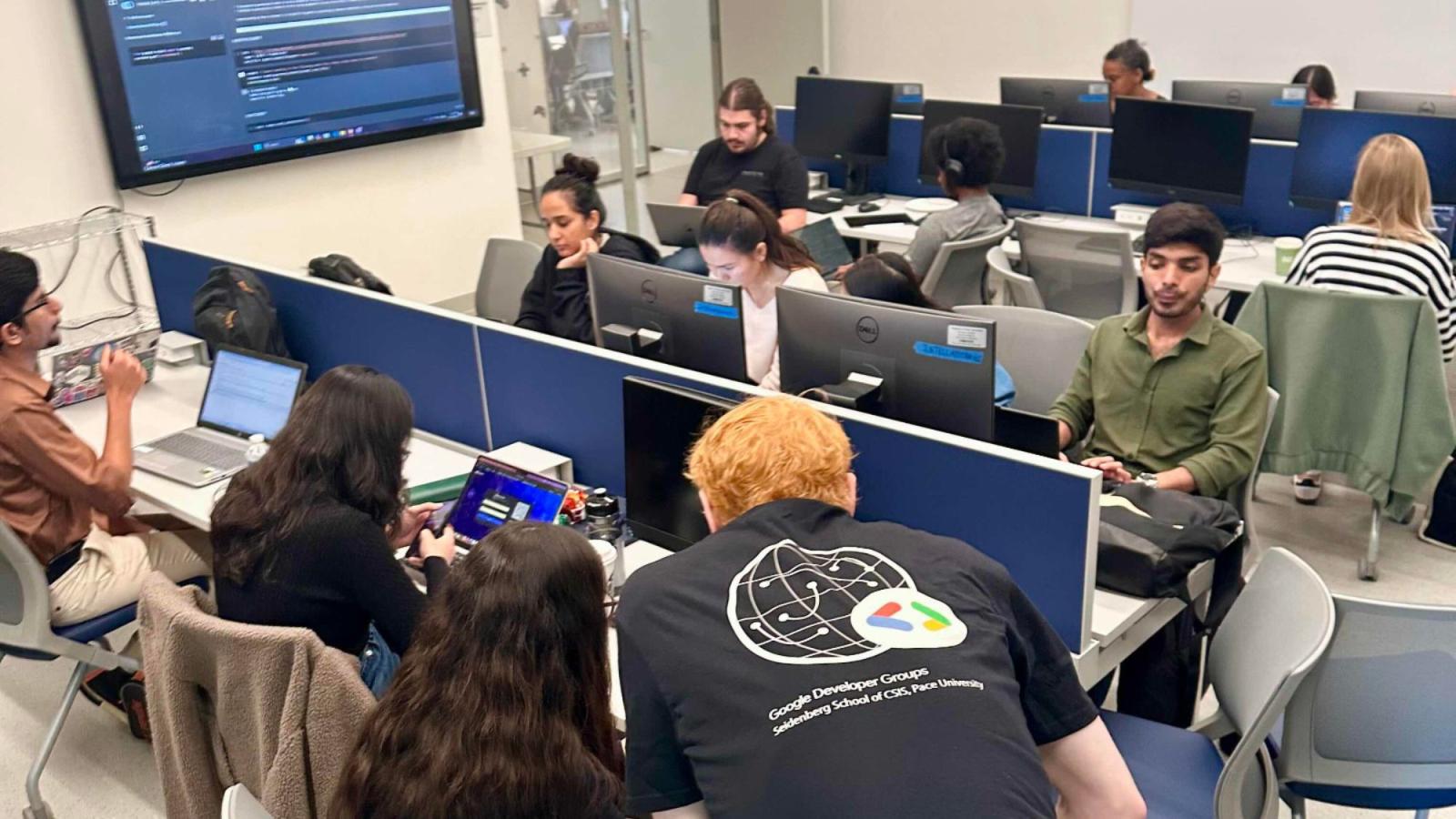 Students from the Seidenberg Google Developers Club collaborating and working on their computers in a classroom.