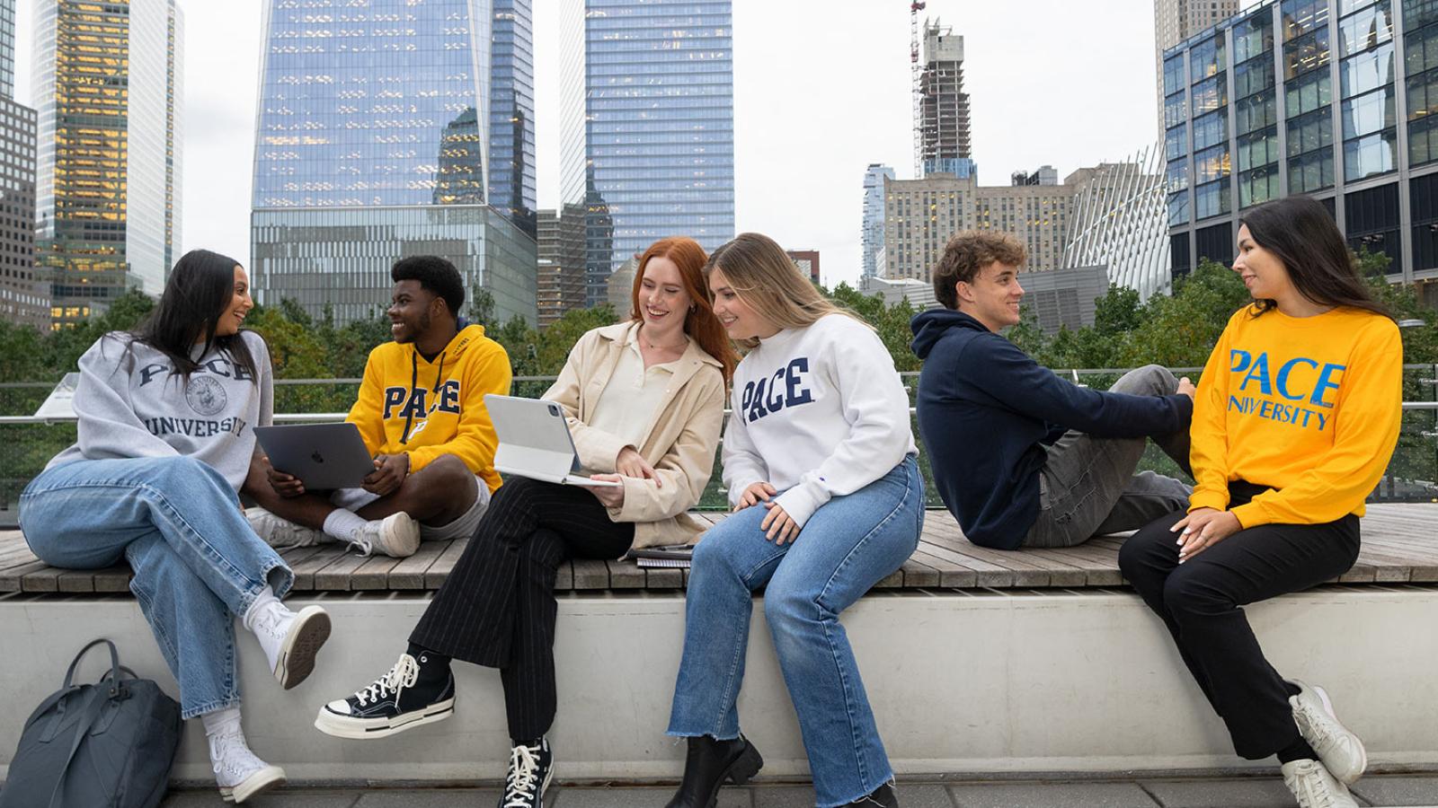 Group of Pace University students sitting on a wall in Manhattan and hanging out.