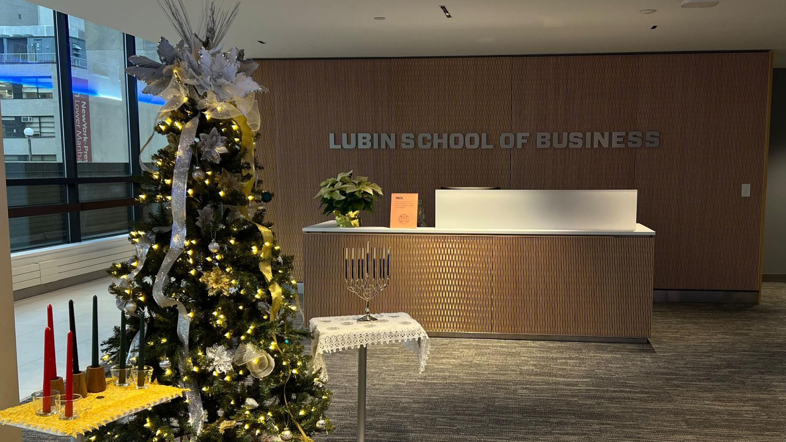 lobby of the Lubin School of Business at Pace University in New York City with Christmas tree, Hanukah menorah, and Kwanzaa table with candles