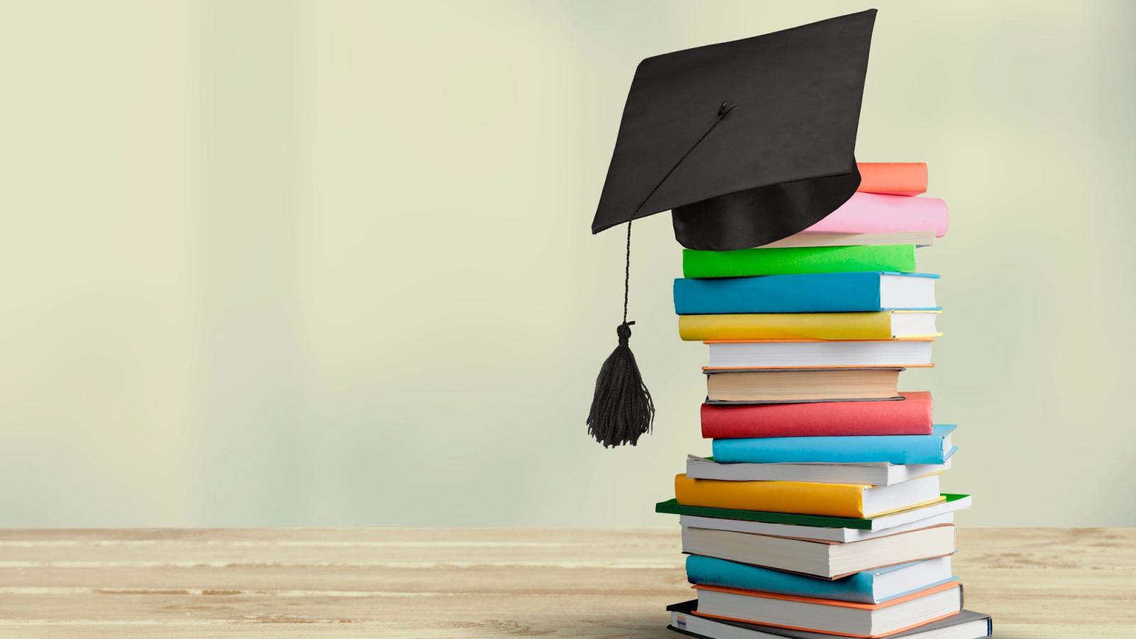 Stack of books with a motarboard on them. 