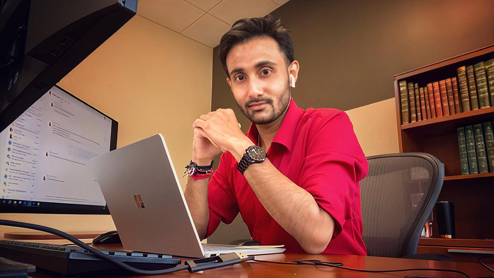 Pace student Soumyadip Chatterjee ’23 sits at a desk in front of a laptop and looks at the camera