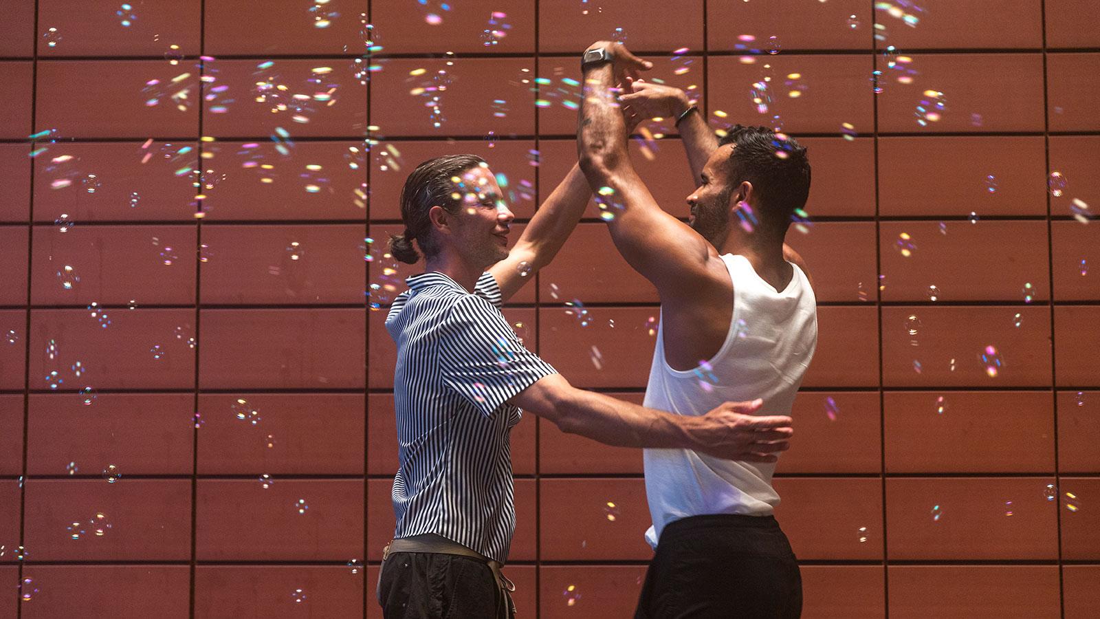 Image of two people dancing with bubbles all around called Slow Dance Project by Yung Oh Le Page displayed in the We're Home exhibition in the Pace University Art Gallery.
