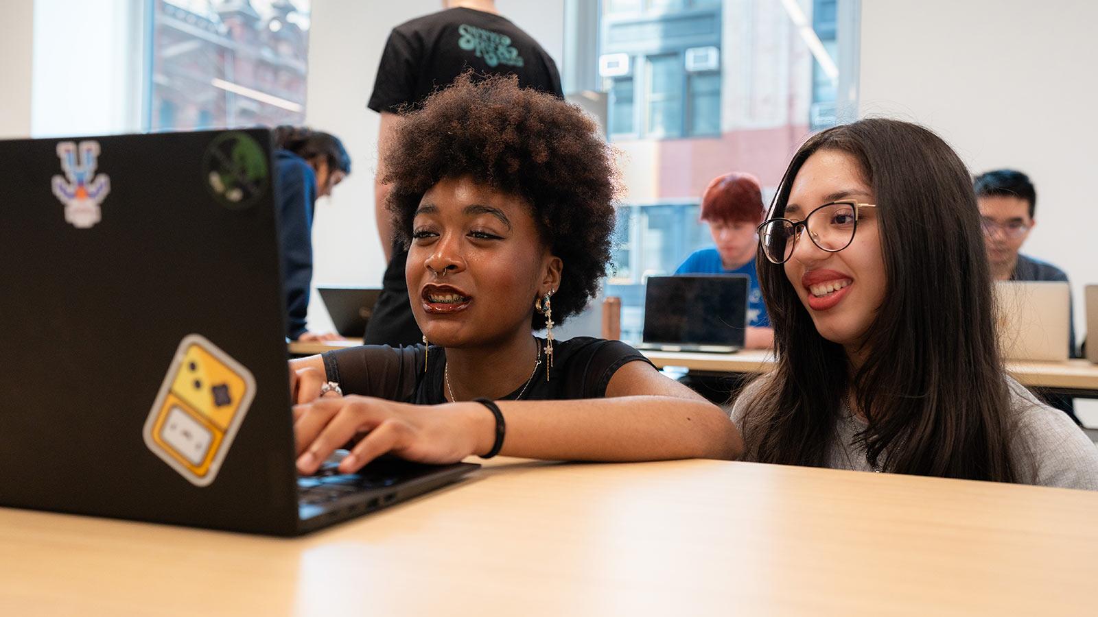 Two female Pace students play a game on a laptop