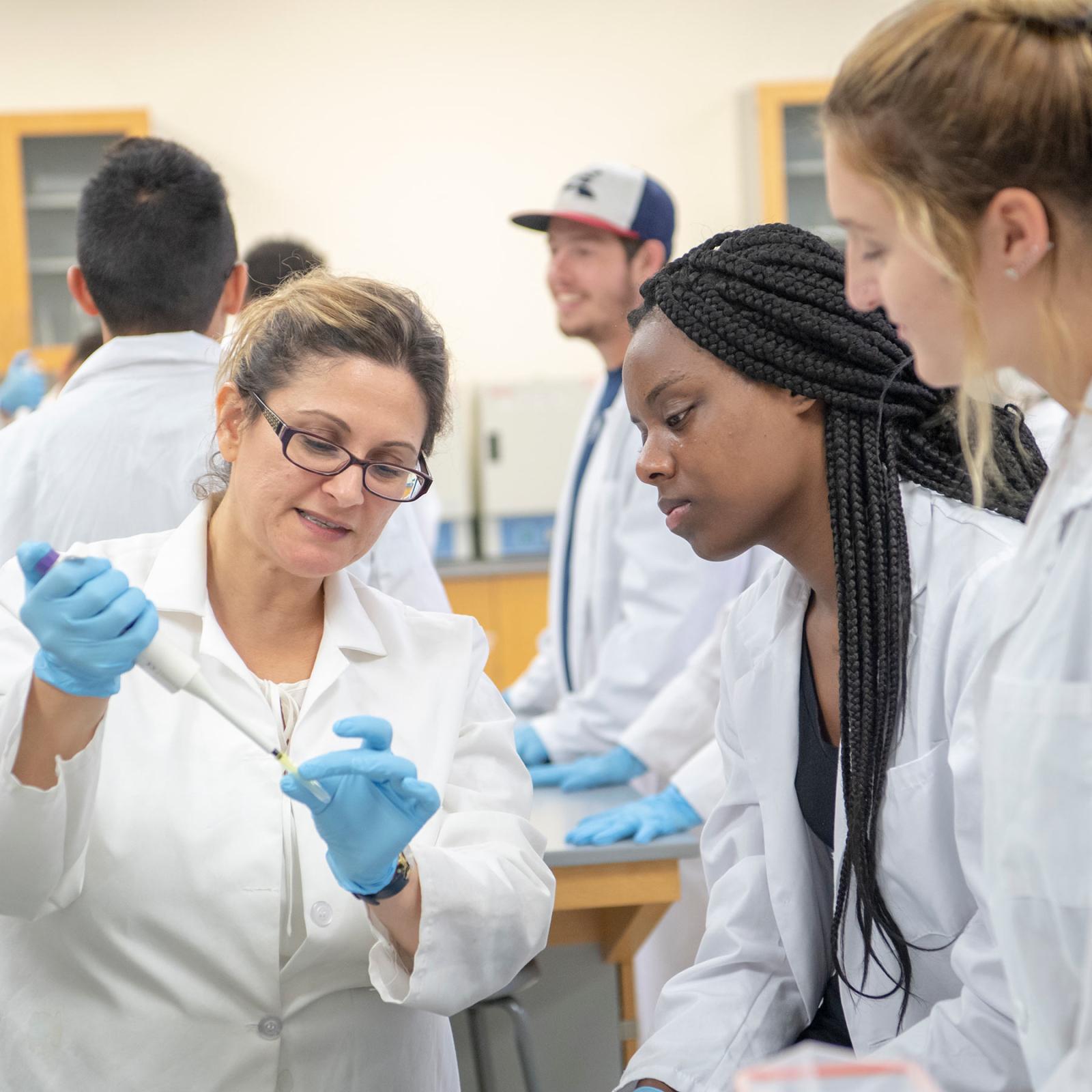 Faculty member working with students in a lab.