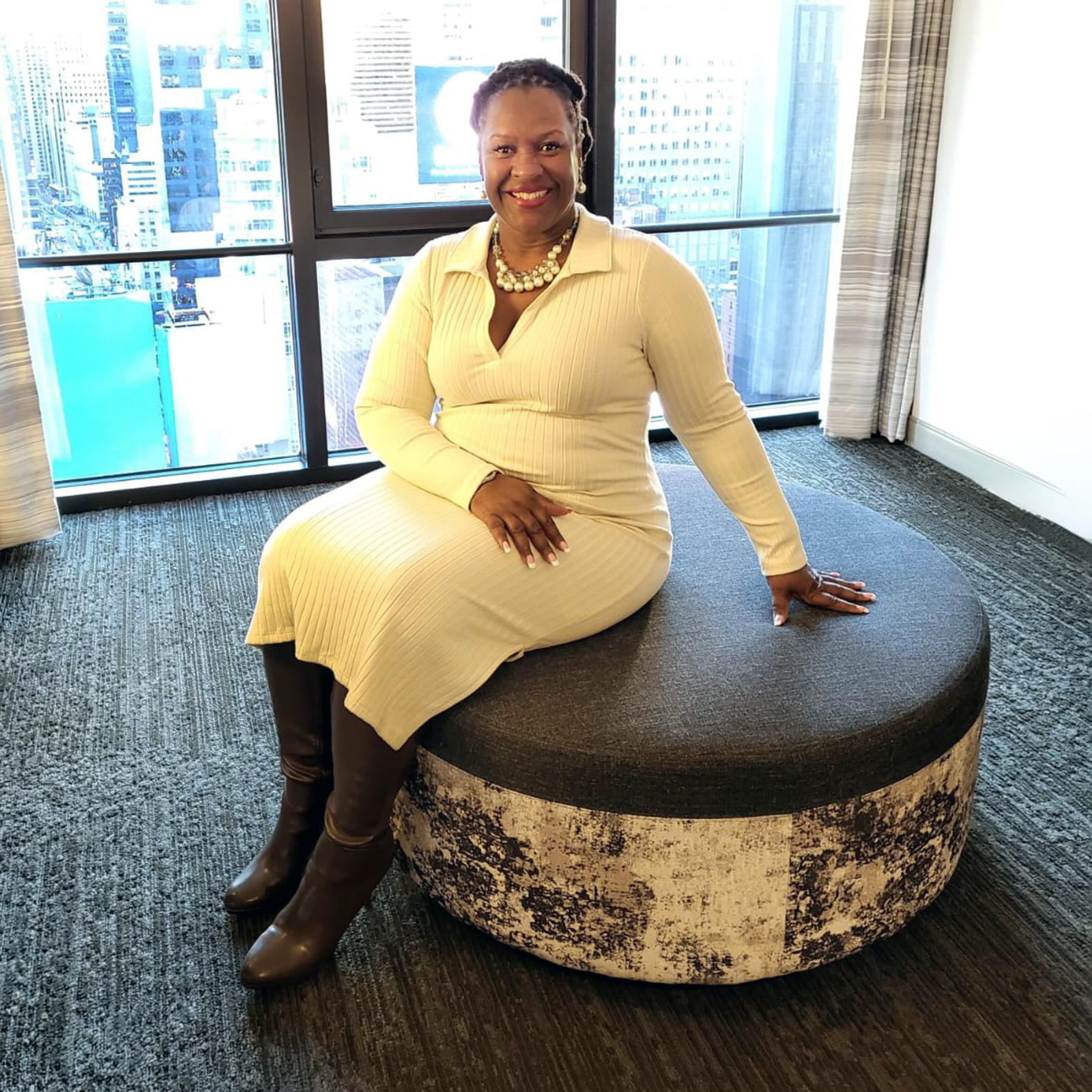 Katina Hill Thompson wearing a white dress and posing for the camera. 