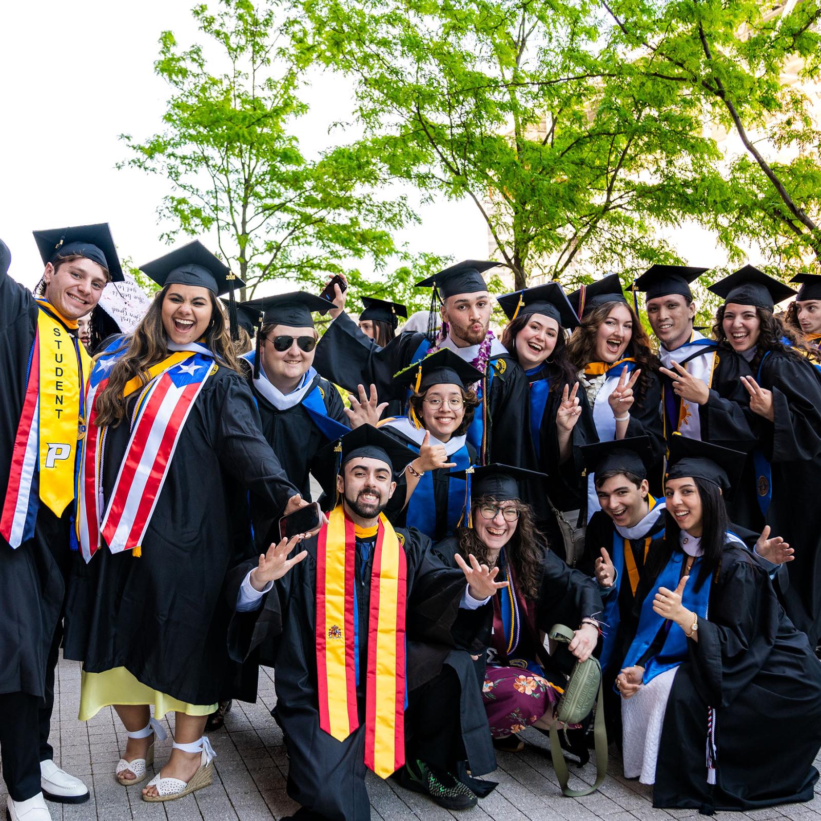 13 recent Pace University graduates posing for a photo at the 2024 commencement ceremony.