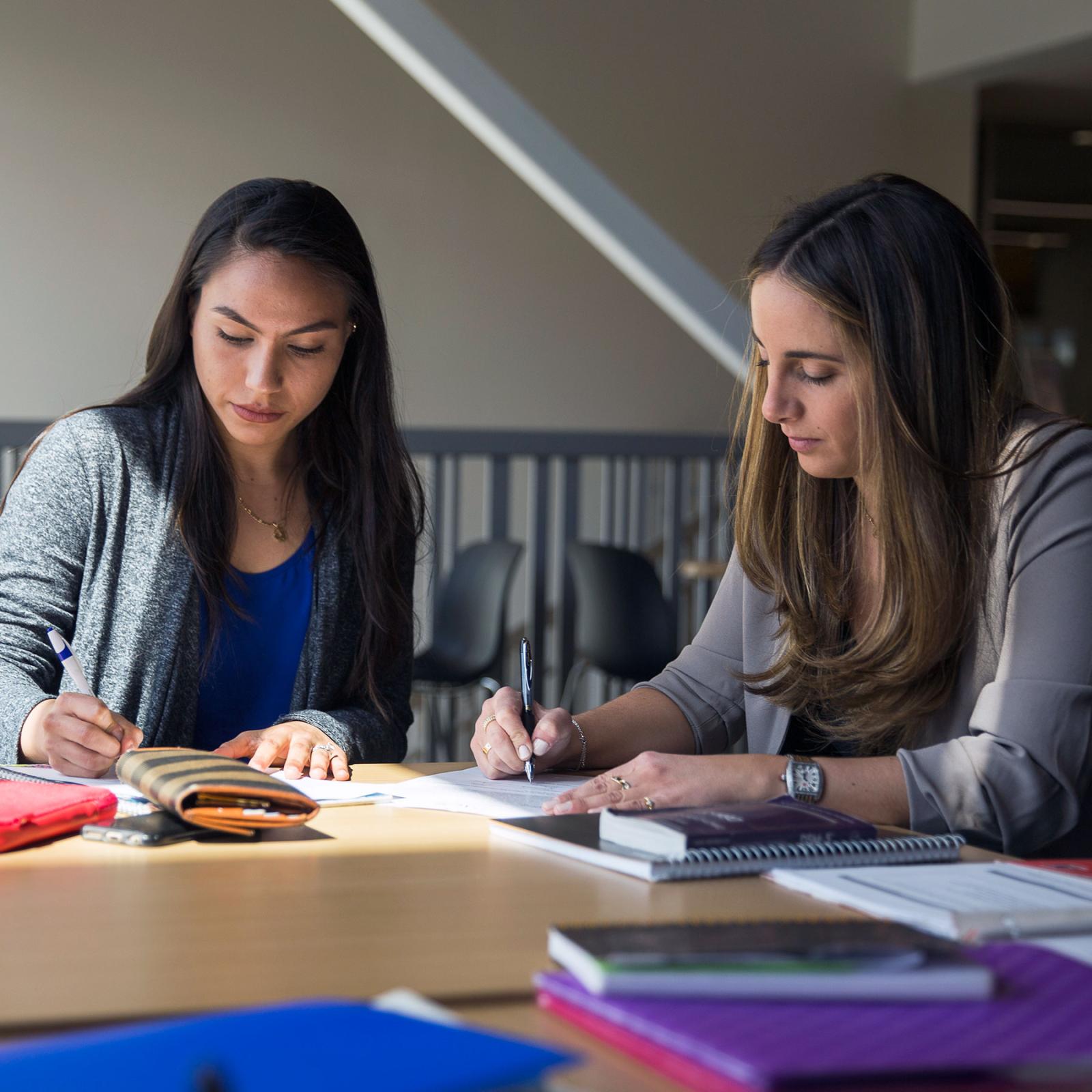 Two Pace University Mental Health Counseling students writing at a desk together
