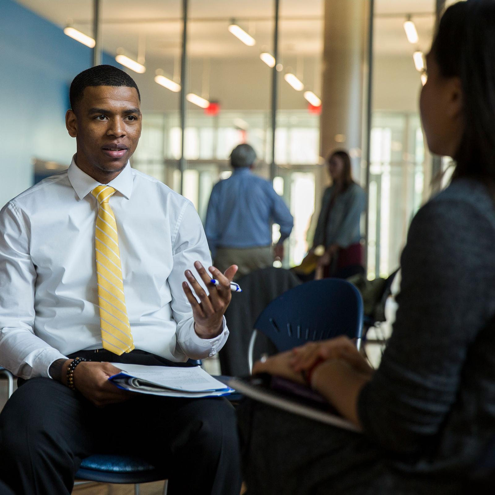 Pace University's Mental Health Counseling student sitting in a chair and speaking with a person across from him