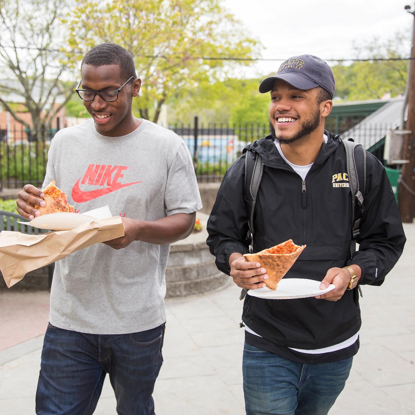 Two Pace University Students walking in the town of Pleasantville NY while eating pizza.