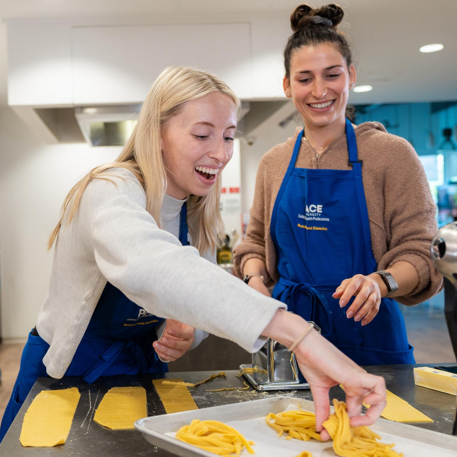 Two students from the Pace University College of Health Professions cooking pasta in the Teaching Kitchen