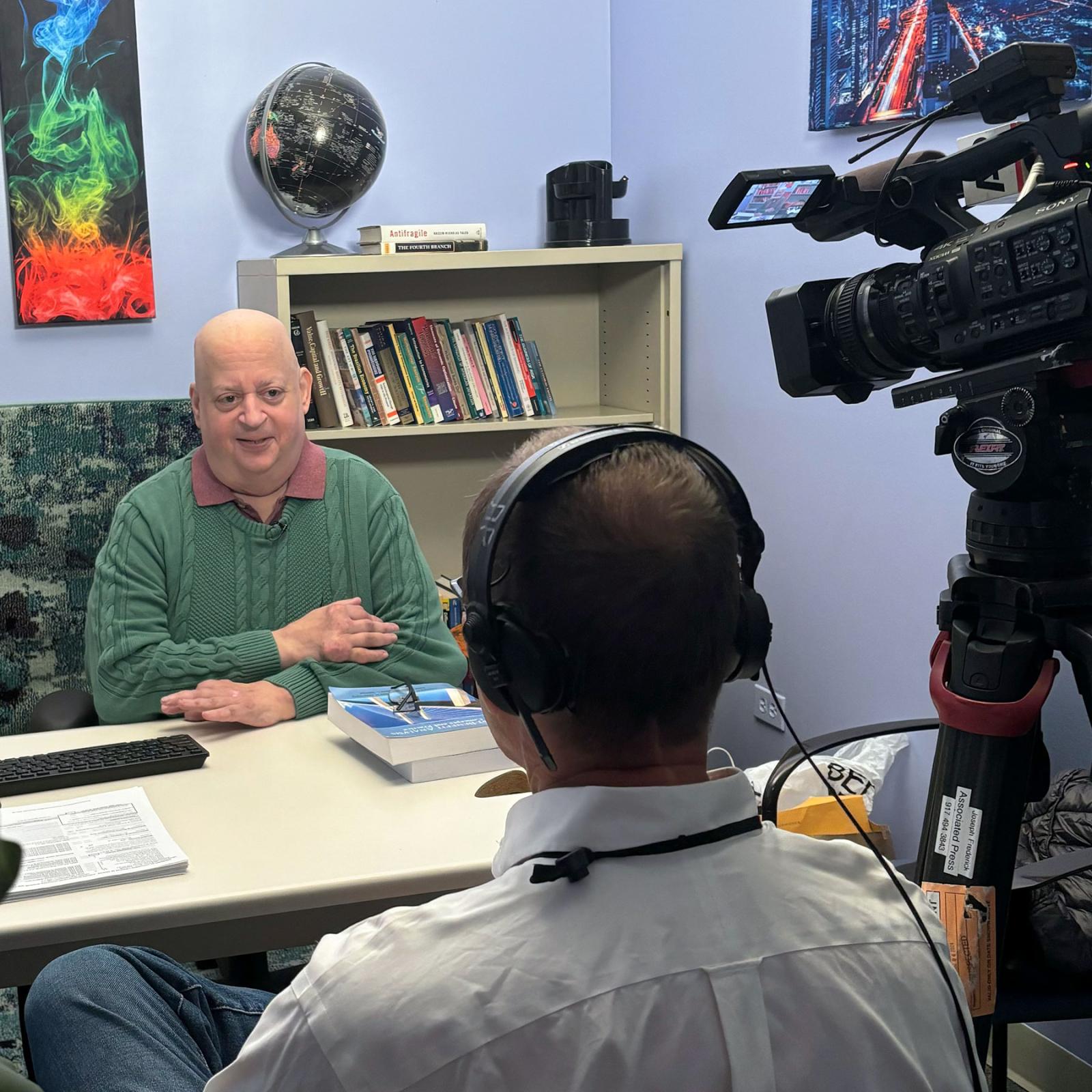 Pace University Clinical Associate Professor of Economics Mark Weinstock, MA, being interviewed by a person from Associated Press with a video camera