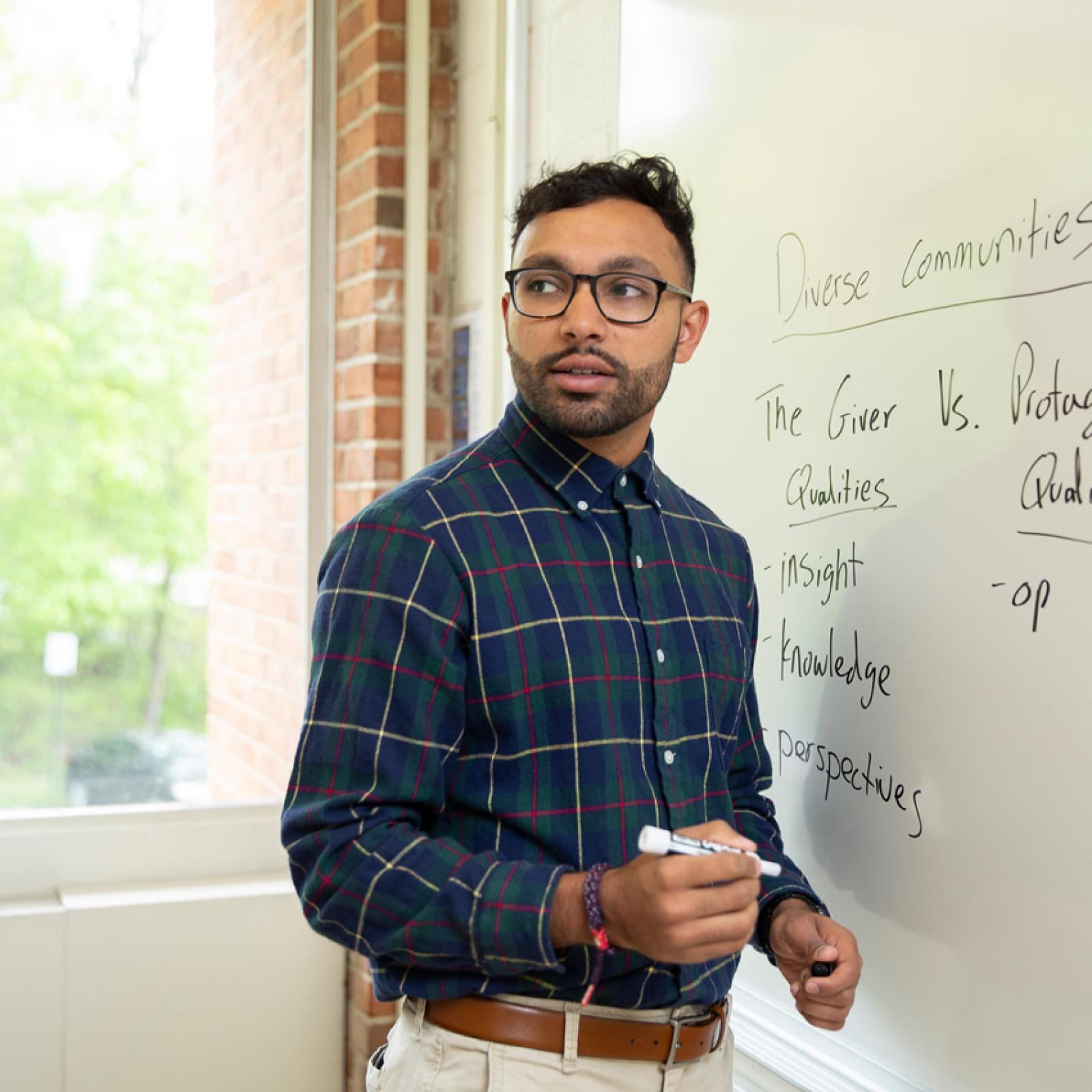 A man working on a white board at Pace University.