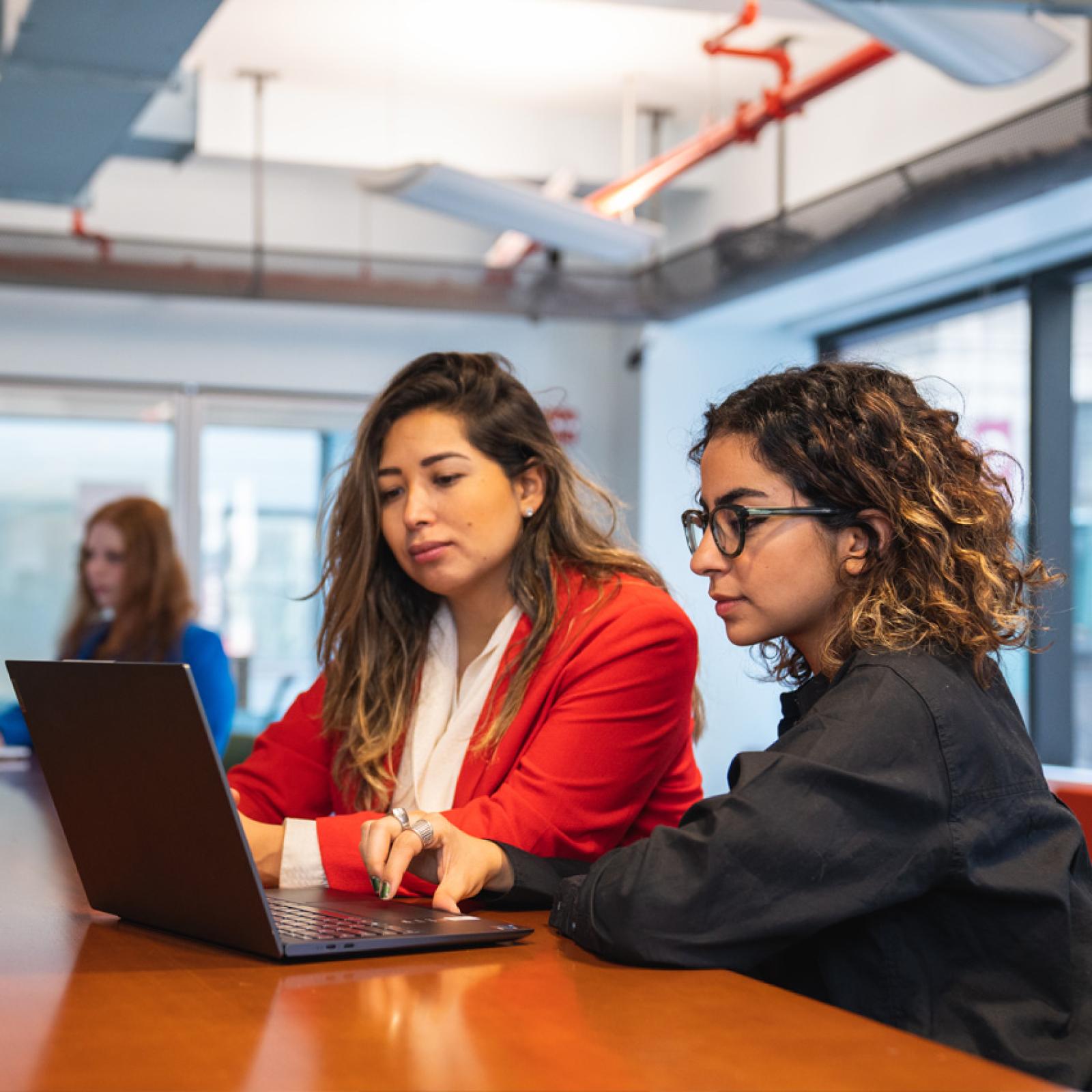 Two professional women speaking to each other in an office.