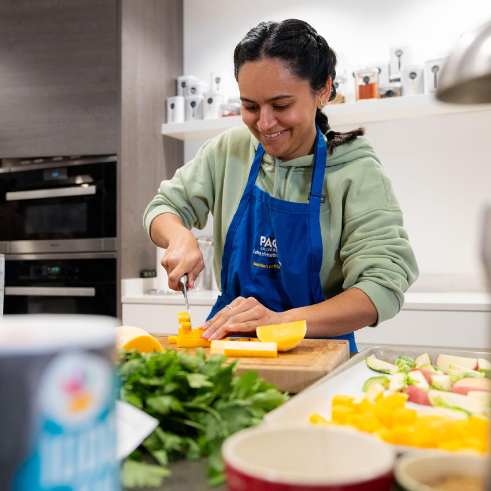 A Pace University nutrition student chopping vegetables. 