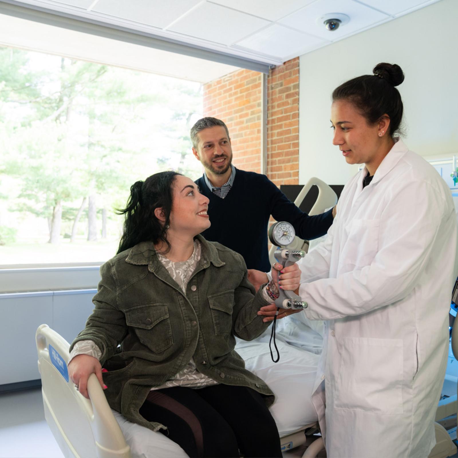 Pace University OT students working with a standardized patient at the bedside. 