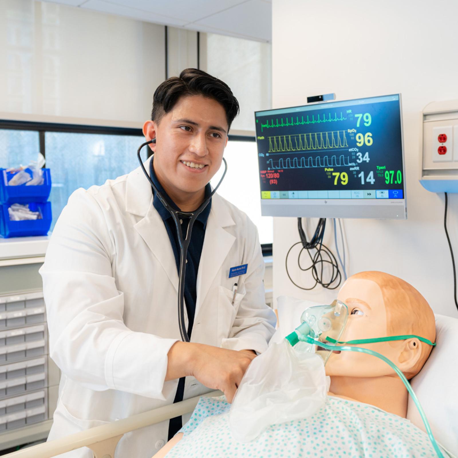 A Pace PA student doing a procedure at the bedside of a medical mannekin. 