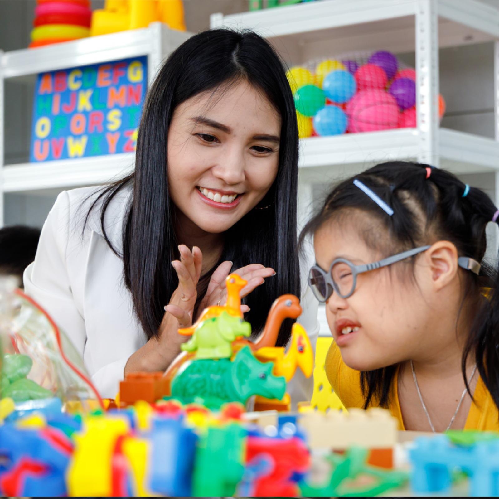 A teacher working with a student in a special education classroom setting.