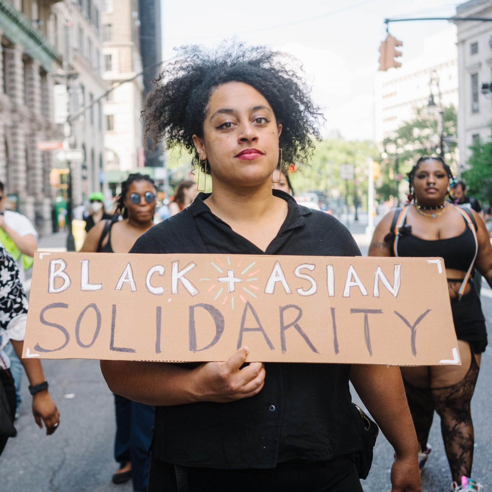 Photo by Cindy Trinh of a person of color holding a sign that says Black Asian Solidarity.