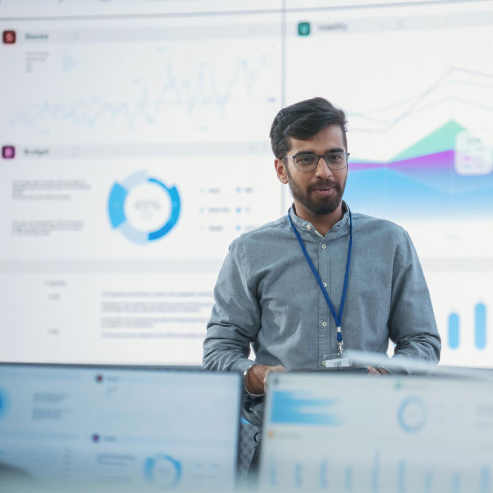 A man standing in front of screens showing data science.