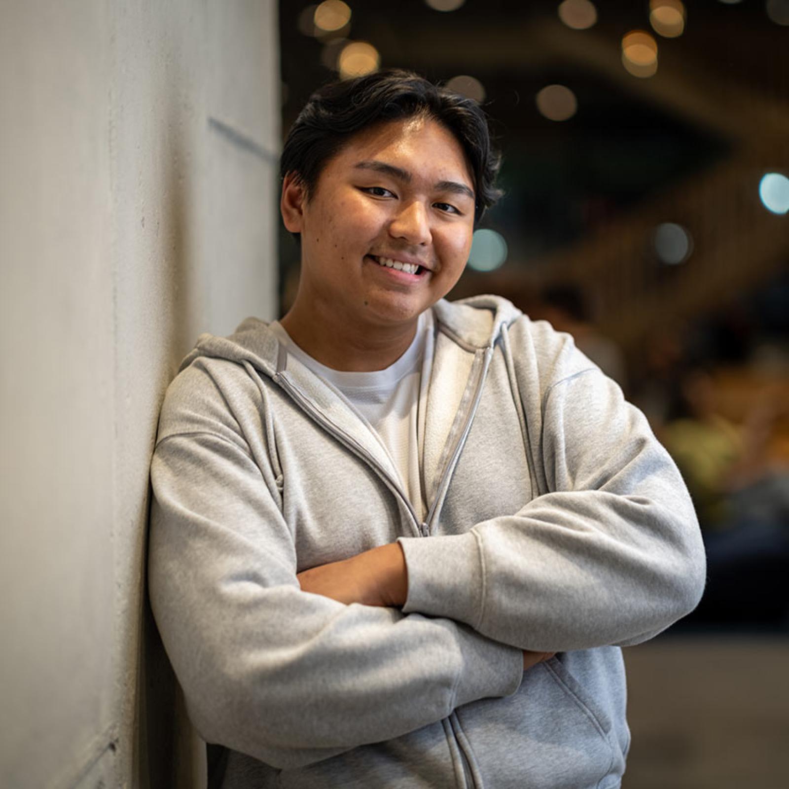 A Pace student leans against a wall and smiles