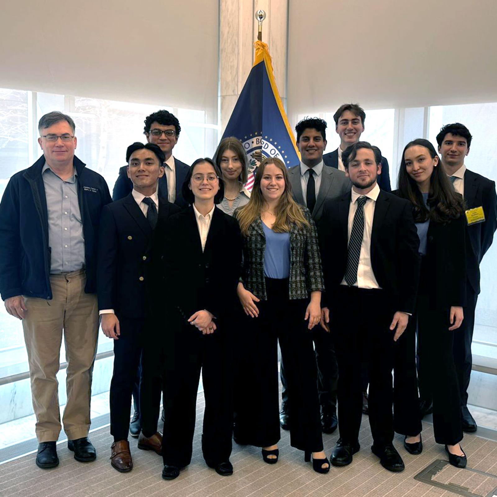 The Pace University Federal Reserve Challenge team standing in front of windows after winning the New York Regional College Federal Reserve Challenge competition